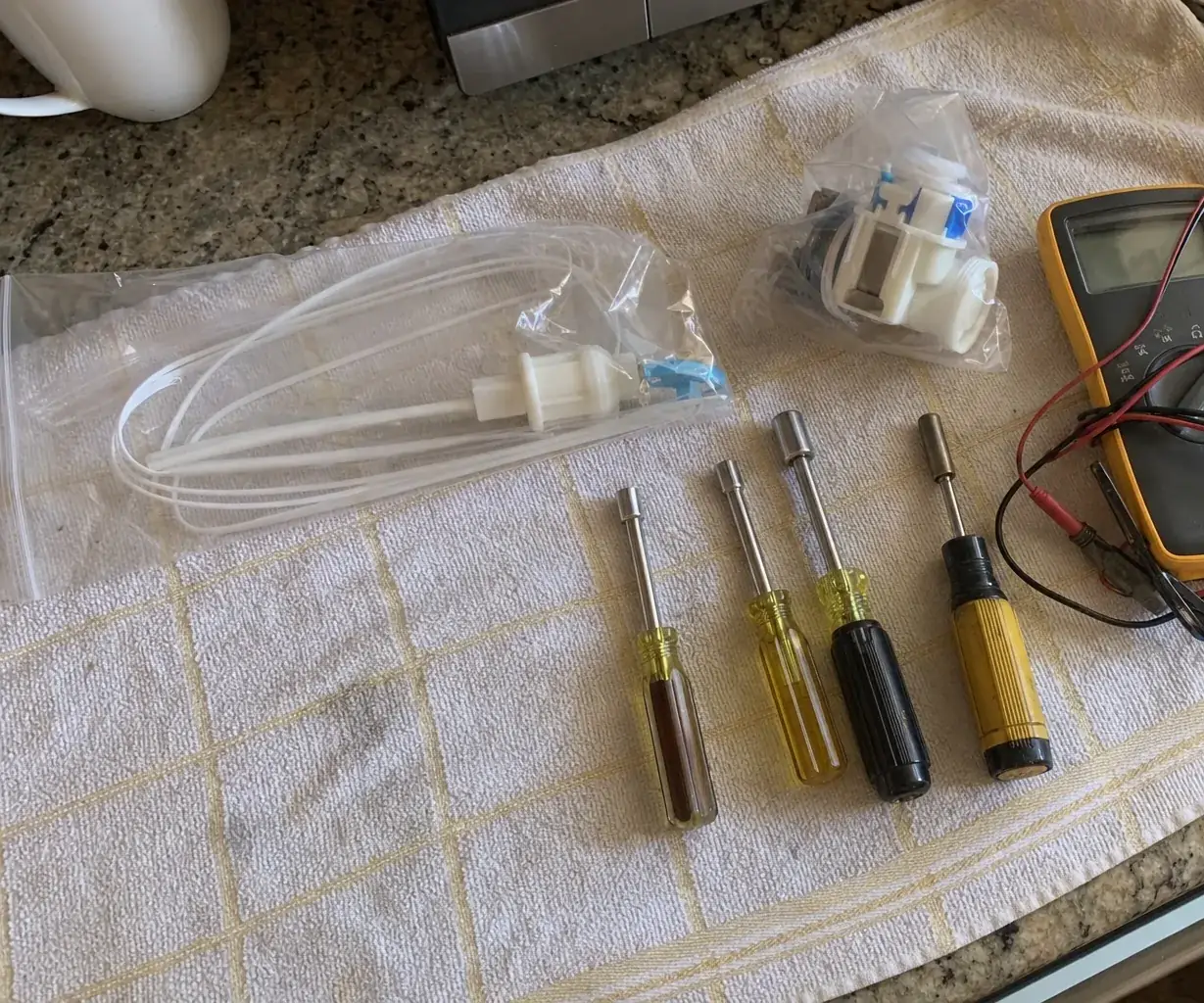 A close overhead crop of a multimeter and a nut driver lying on a creased kitchen towel